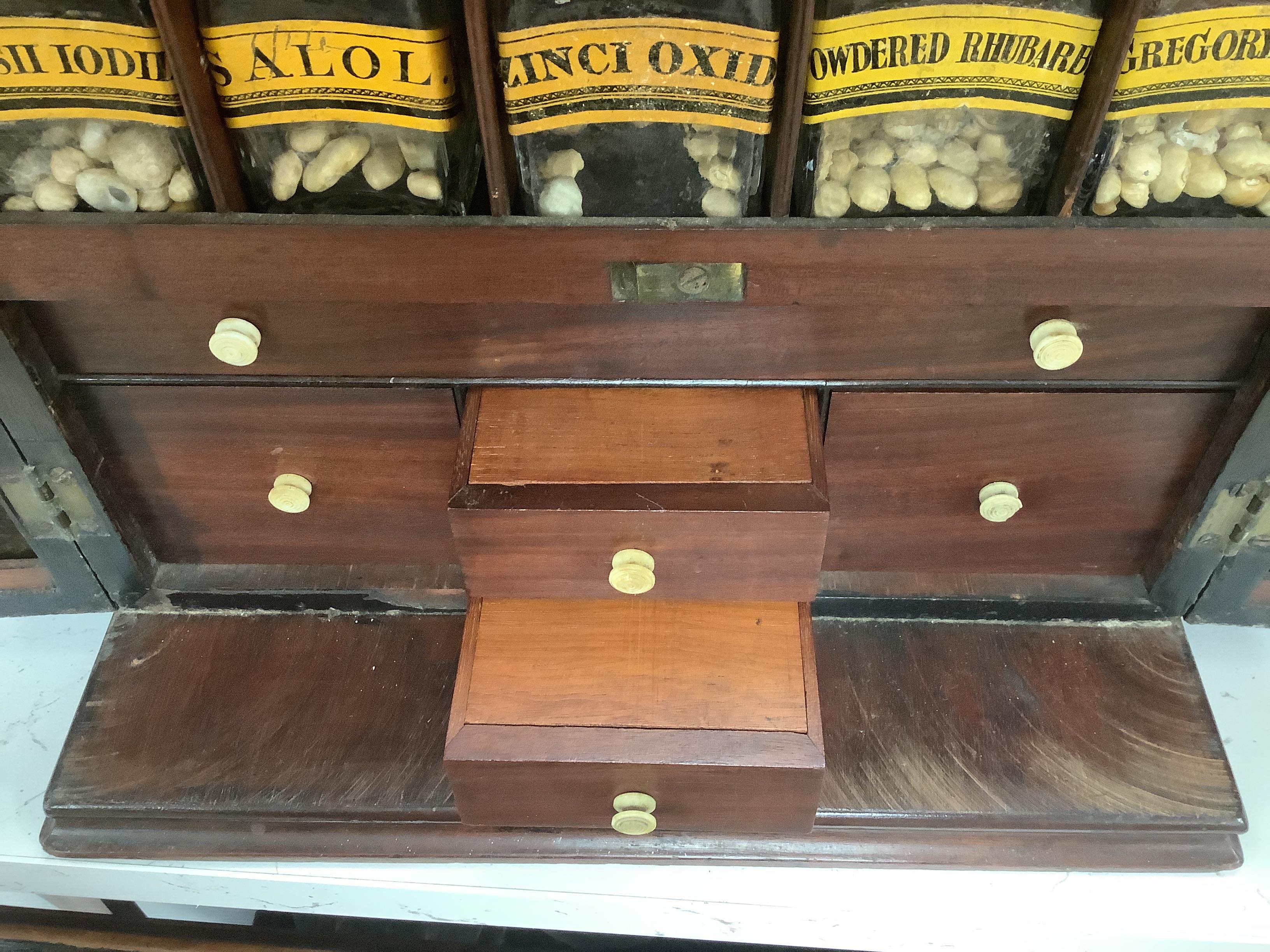 A Georgian mahogany domestic medicine chest, with bone drawer knobs and escutcheons, containing a number of glass square section drug bottles, fitted drawers containing scales, a pestle and mortar, etc., 29cm wide, 25cm